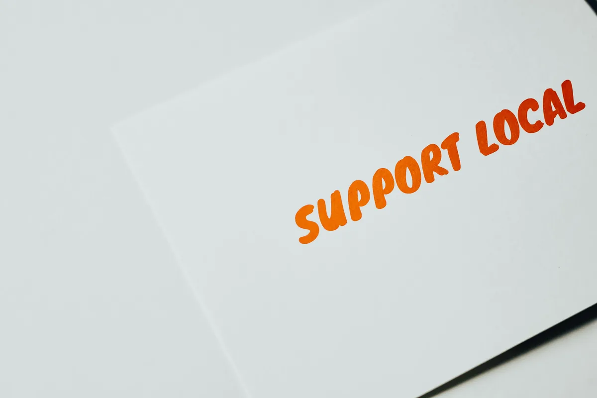 Close-up of Support Local message on white paper, encouraging local support.